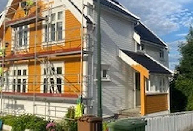Hvitt og gult hus med stillas